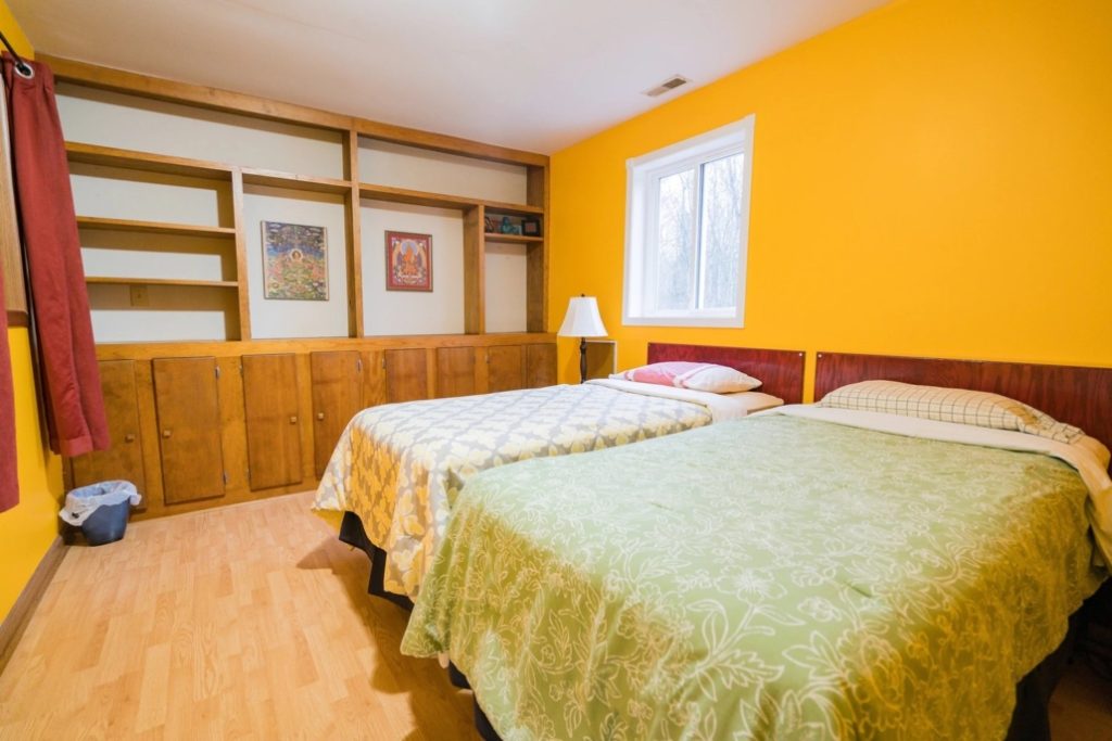 Photo showing two double beds in a retreat room, with yellow walls