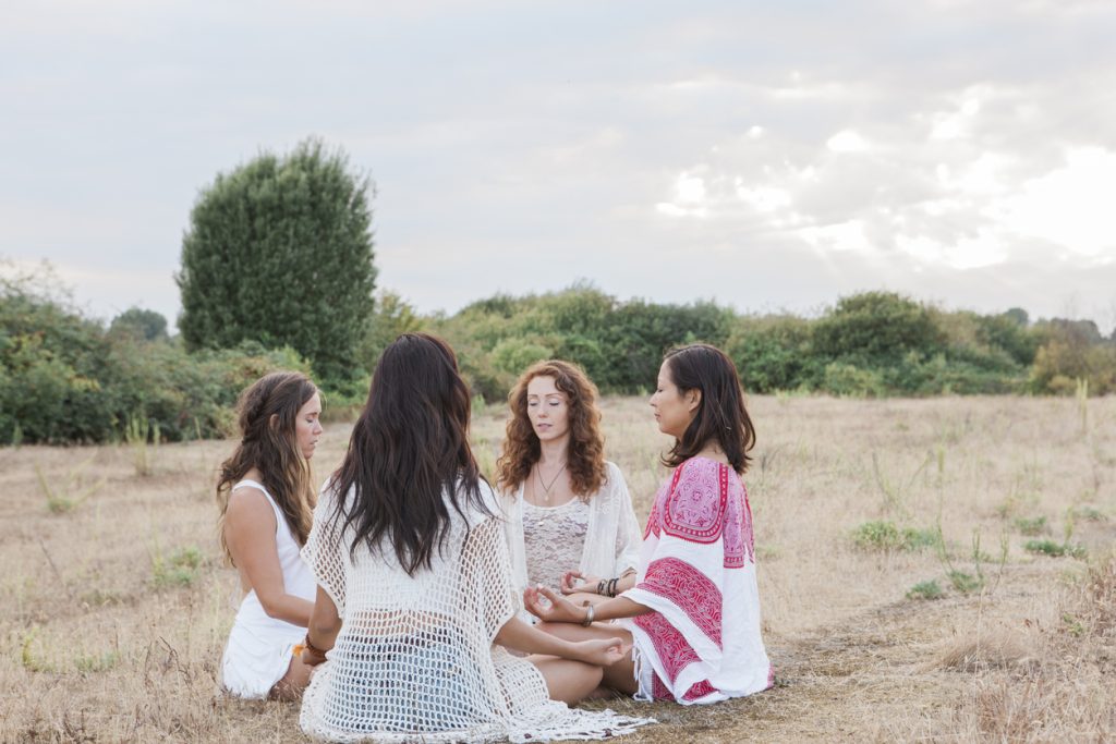 Four women sitting in a circle, in a field in nature